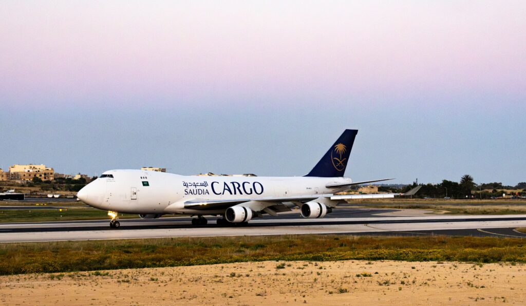 A Saudia Cargo plane on a runway at twilight with a serene sky background.